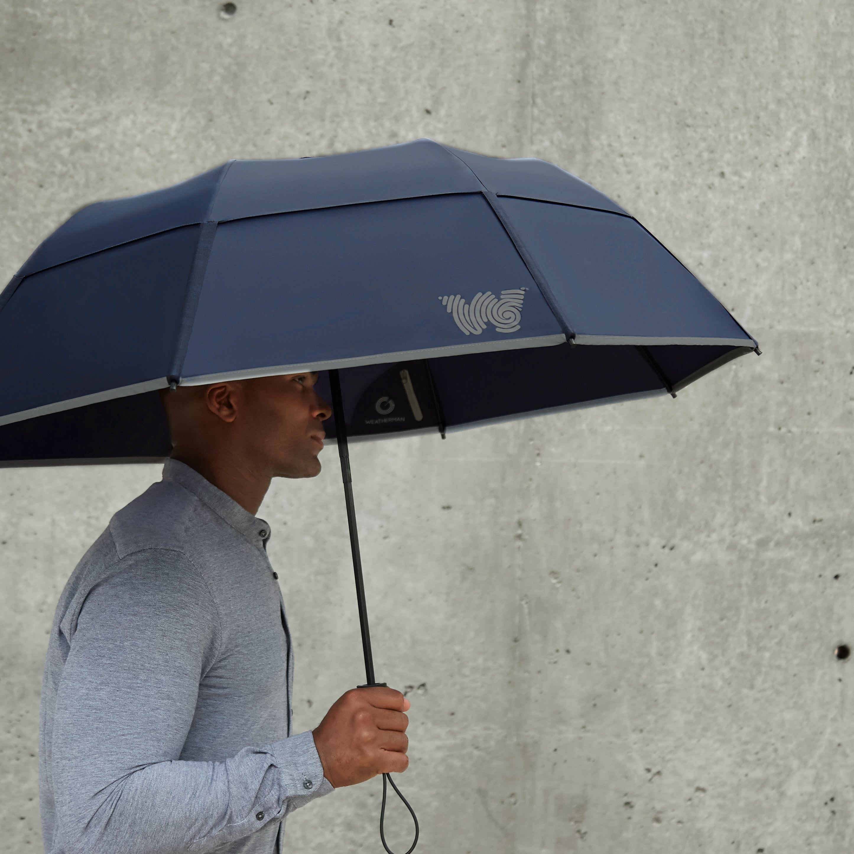 Man walking with Weatherman Collapsible Umbrella in navy blue.