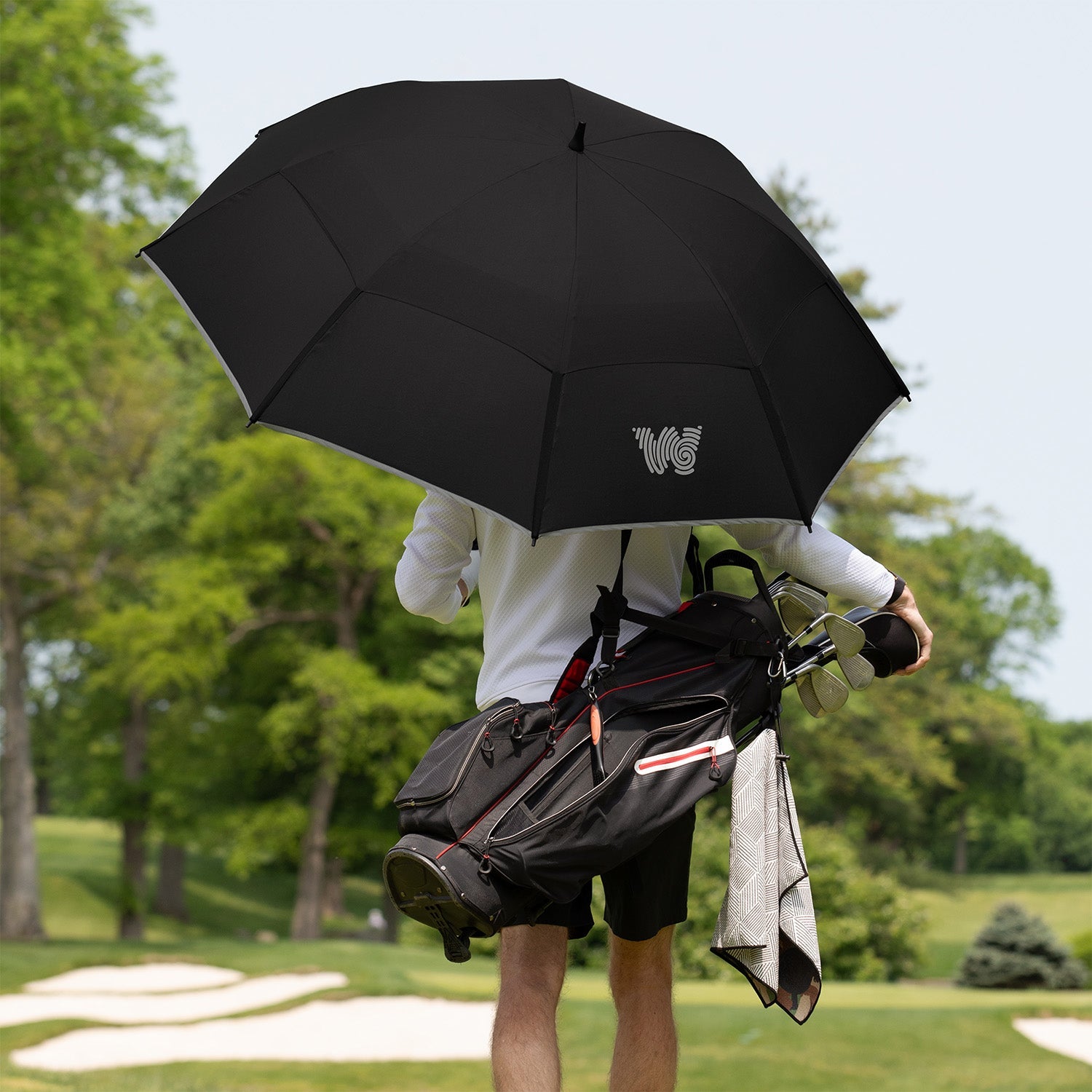 Man walking on golf course with Weatherman Golf Lite Umbrella in black.